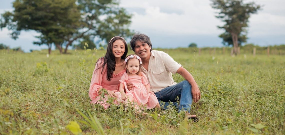 a man, woman and child are sitting in a field