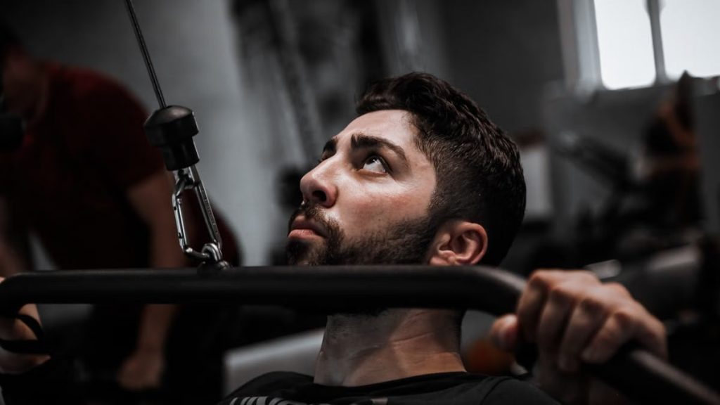 Muscular man working out with determination on gym equipment.