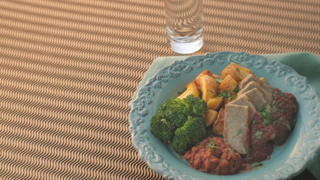 A beautifully presented dish with sliced meat, broccoli, and potatoes on an ornate plate.